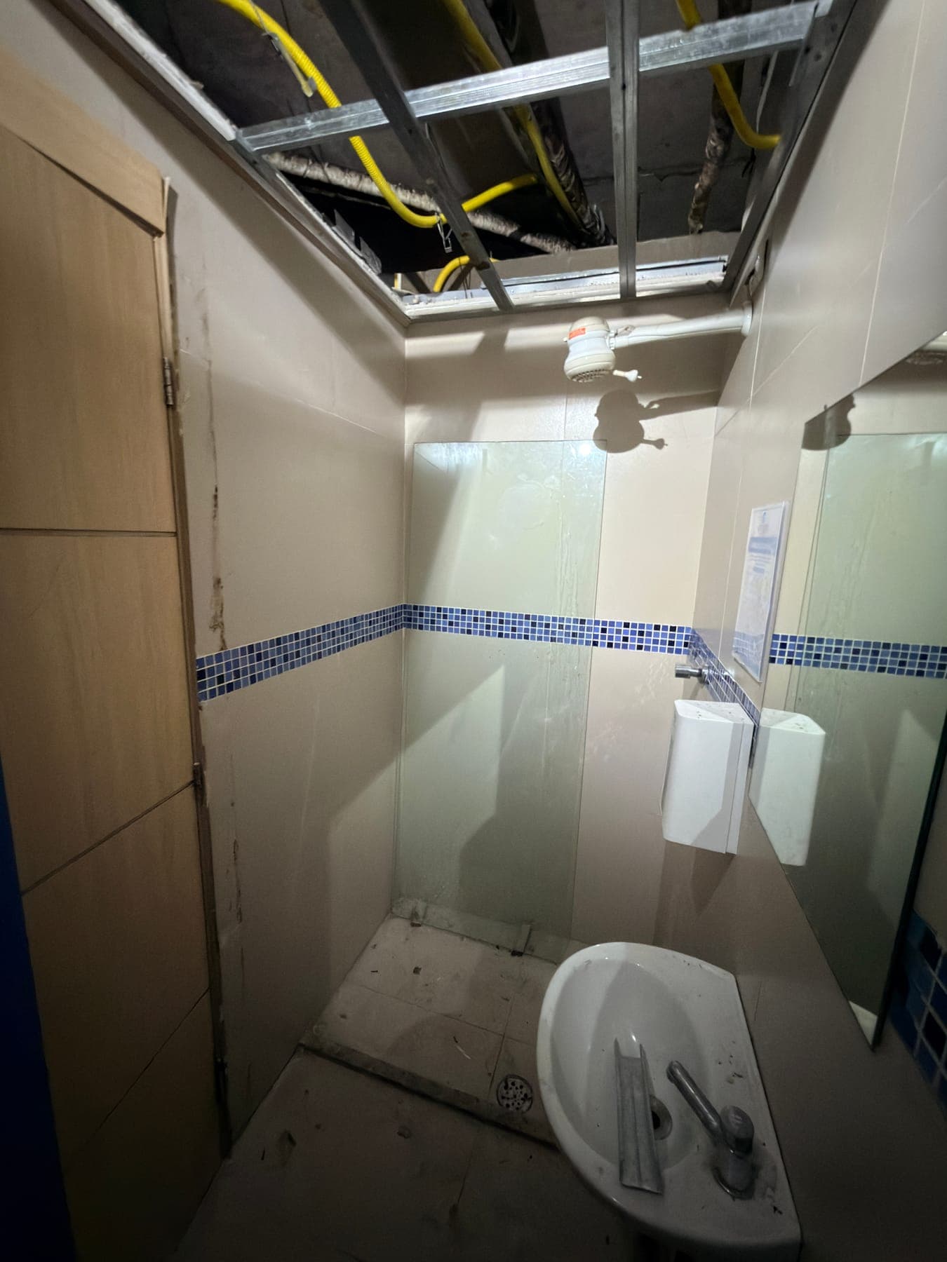 Obra em andamento: banheiro em reforma com placa amadeirada na parede e forro aberto